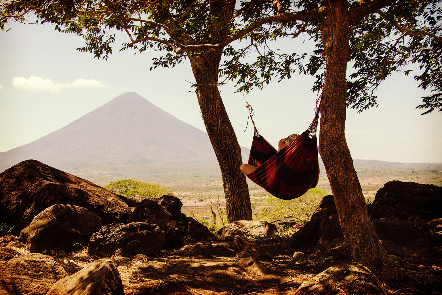Person relaxing in a hammock with a volcano in the background, illustrating the lifestyle appeal of living in Nicaragua and residency options