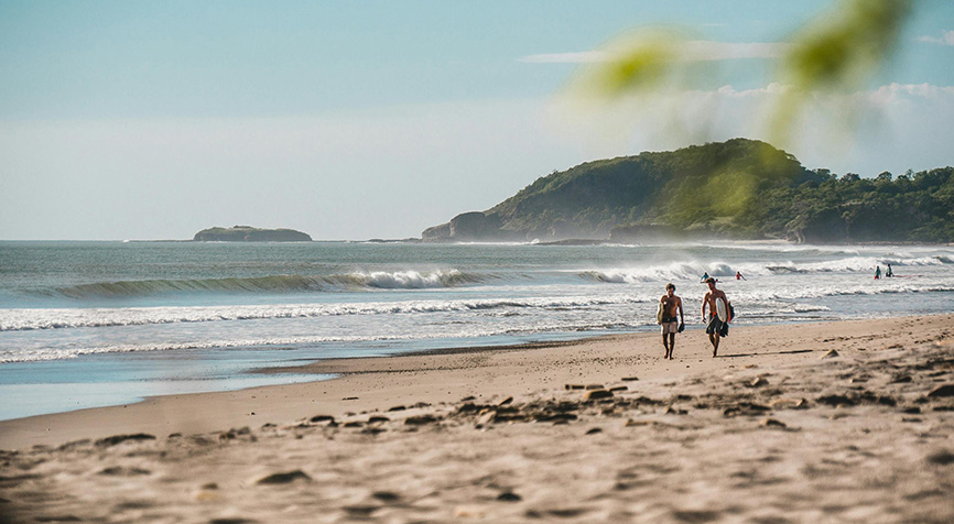 Two surfers on a beautiful Nicaraguan beach with a volcano in the background